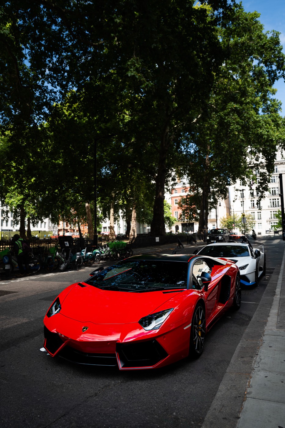 Red Lamborghini Aventador SVJ parked on a tree-lined street in Mayfair, London